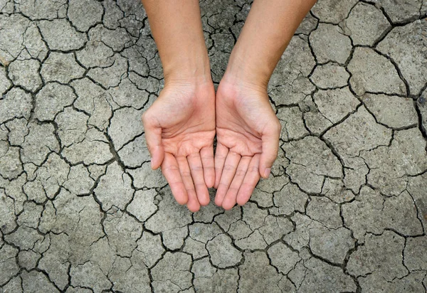 Asian woman\'s hand On dry, cracked soil