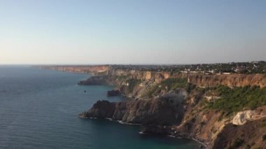 Ufka kadar uzanan turkuaz mavi denizin güzel manzarası. Saf kaya, gün batımından önceki güneş tarafından aydınlatılır. Sakin dalgalar küçümsenmiş kayalara çarpıyor.