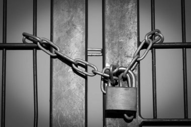 Kilitlemeyi simgeleyen çelik zincirli demir çitli asma kilit.