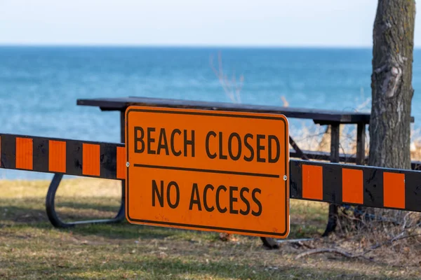 Beach closed sign no access with sand and blue water in background