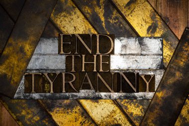 Photo of real authentic typeset letters forming End The Tyranny text on vintage textured grunge silver gold and copper layered background clipart