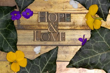 Gerçek otantik harf dizisi fotoğrafı Umut ve Aşk metni oluşturan renkli çiçeklerle klasik desenli grunge bakır arka plan
