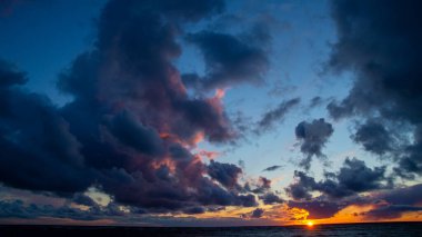 Kumsalda gün batımı, dalgalar, dramatik gökyüzü, dramatik bulutlar.
