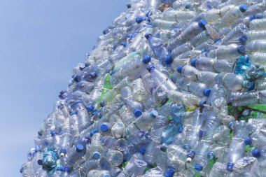 Arka planda güzel mavi gökyüzü olan bir sürü plastik atık şişesi.