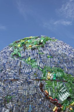 Dünyanın plastik şişelerden ve diğer plastik atıklardan oluşan bir kısmı arka plan olarak koyu mavi gökyüzü. resimler dikey olarak çekildi