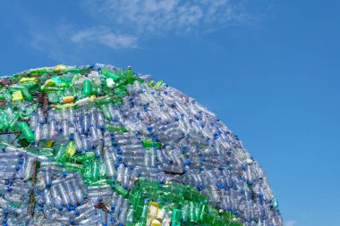 Dünyanın dörtte biri plastik şişelerden ve arkaplan olarak atıklardan oluşuyor. Güzel mavi bir gökyüzü.