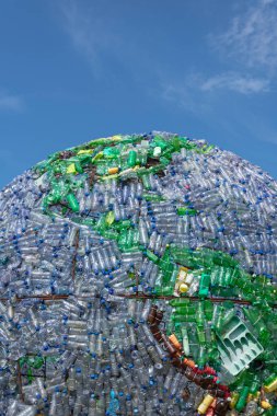Dünyanın plastik şişelerden ve diğer plastik atıklardan oluşan bir kısmı arka plan olarak koyu mavi gökyüzü. resimler dikey olarak çekildi