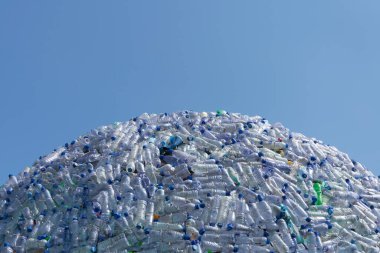 Yarı dairesel plastik atık dağı, güzel mavi arka planı olan plastik şişeler.