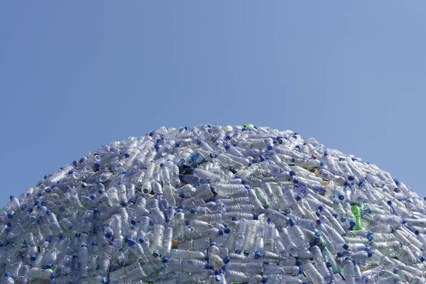 полукруглая гора пластиковых отходов, пластиковые бутылки с красивым синим фоном
