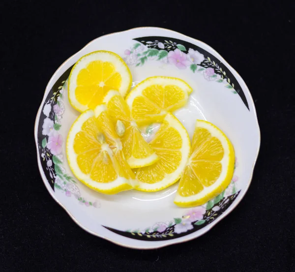 Siyah arka planda bir tabakta limon dilimleri