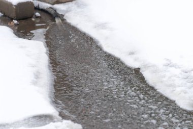 Buzun altından akan suya ayrıntılı bir bakış, musluktan akan su dereye akar.