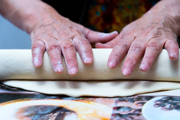 Fırıncı un ahşap mutfak masasına hamur koyar.