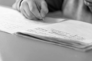 Konsantre çocuk ödevini evde yapıyor. Çocuk oturuyor ve kitap ve dizüstü bilgisayarlar için arıyorsunuz