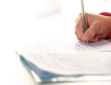 Konsantre çocuk ödevini evde yapıyor. Çocuk oturuyor ve kitap ve dizüstü bilgisayarlar için arıyorsunuz