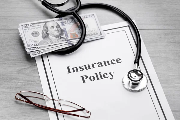 Ziektekostenverzekering beleid. Stethoscoop, bril, dollar op een tafel — Stockfoto