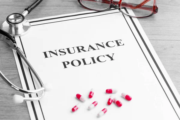 Ziektekostenverzekering beleid. Stethoscoop, bril, pillen op tafel — Stockfoto