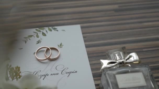 wedding arrangement of flowers, invitations cards, wedding rings and perfumes