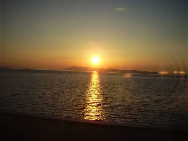 Akşam yemeğinden önce gün batımı otel penceresinden izledi. Güneş ufkun ardında yavaşça batar ve onun parlaklığı ışığı yaratır..