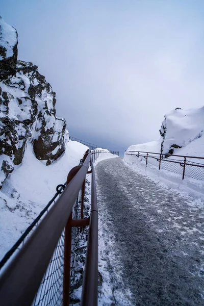 snowy and icy way up left and right rocks and a railing to hold on to. without people iceland