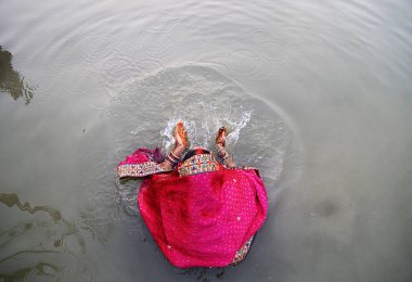 A lady takes a dip  in the holy water in river Ganges on the eve of chhath pooja. Chhath is an ancient Hindu Vedic festival historically native to the Indian subcontinent, more specifically, the Indian states of Bihar, Jharkhand and Uttar Prades clipart