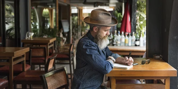 Человек с бородой, пишущий заметки — стоковое фото