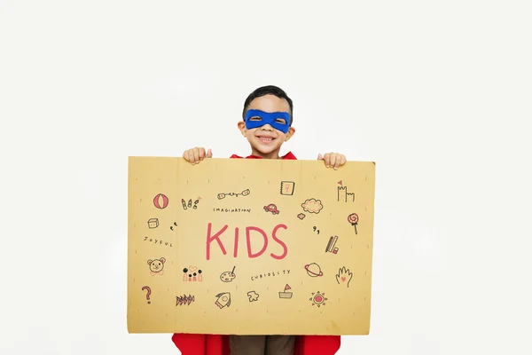Superheld jongen met karton in handen — Stockfoto