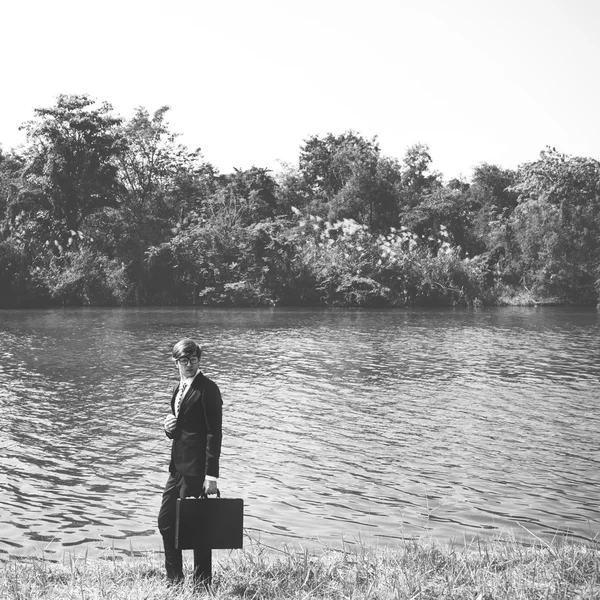 Geschäftsmann mit Aktentasche steht am Fluss, — Stockfoto