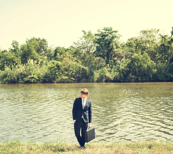 Uomo d'affari con valigetta al fiume — Foto Stock