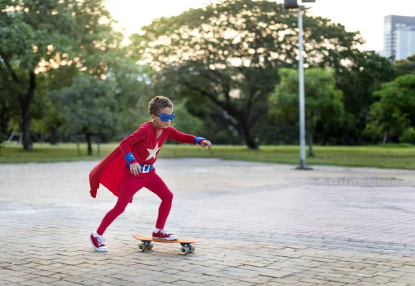 Superhrdinové dítě jezdit na skateboardu — Stock fotografie