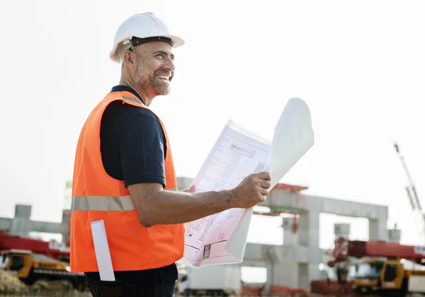 Obrero de la construcción con plan de arquitectura —  Fotos de Stock