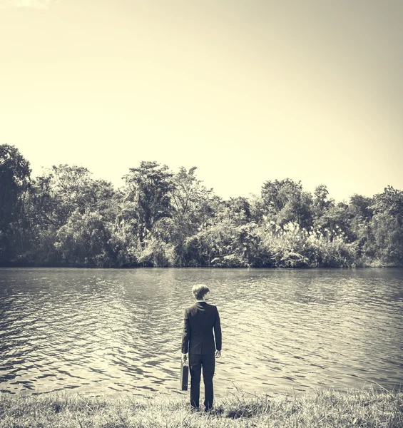 Homme d'affaires avec mallette à la rivière — Photo