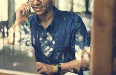 Cep telefonunuzda konuşuyor ve dizüstü bilgisayar kullanarak bir adam