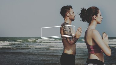 Çiftler plajda yoga yapıyor.