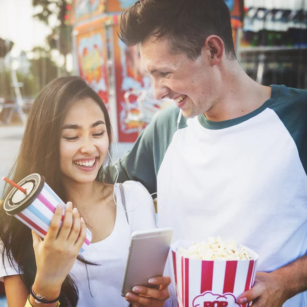 Pareja usando móvil en parque de atracciones — Foto de Stock