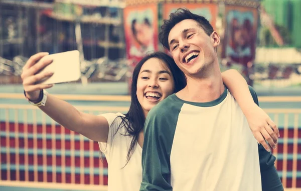 Et par som lager selfie i fornøyelsesparken. – stockfoto