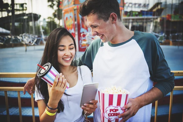 Pareja usando móvil en parque de atracciones —  Fotos de Stock