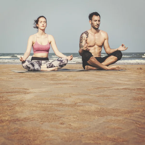 Par som gör yoga på stranden — Stockfoto