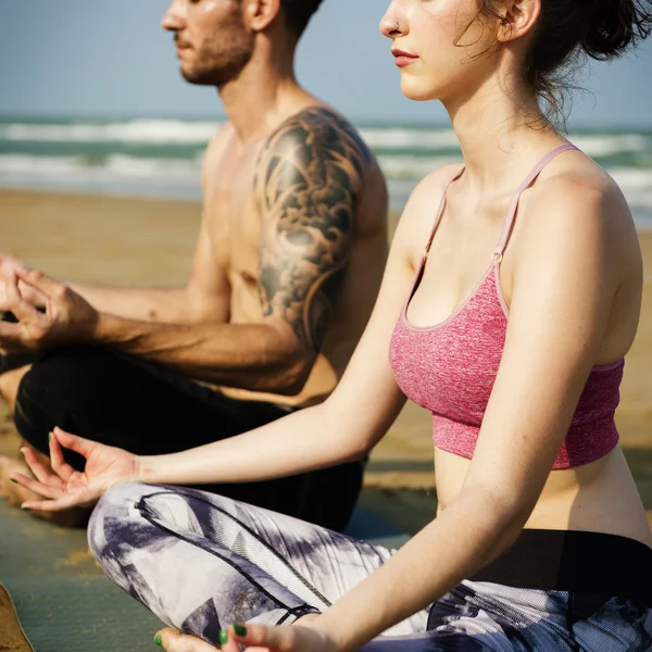 Par som gör yoga på stranden — Stockfoto