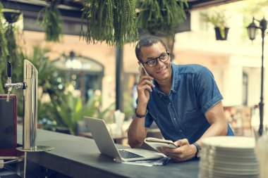 Cep telefonunuzda konuşuyor ve dizüstü bilgisayar kullanarak bir adam