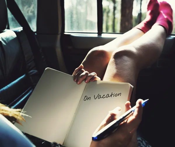 Kvinna som liggande i bilen, håller dagbok — Stockfoto