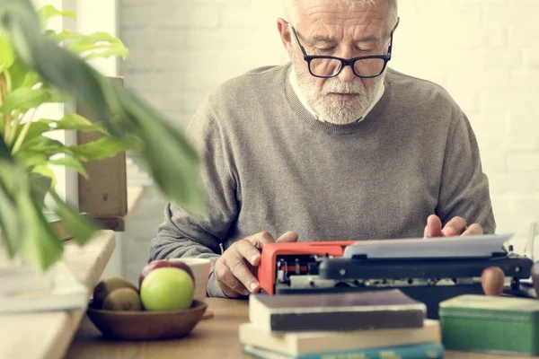 senior man writing on typewriter machine