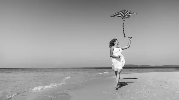 Женщина играет в воздушного змея на пляже — стоковое фото