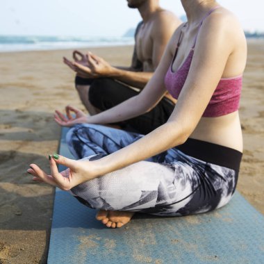 Çiftler plajda yoga yapıyor.