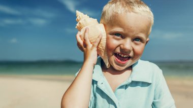 Küçük çocuk dinleme kabuk sahilde