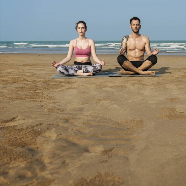 Pár dělá jógu na pláži — Stock fotografie