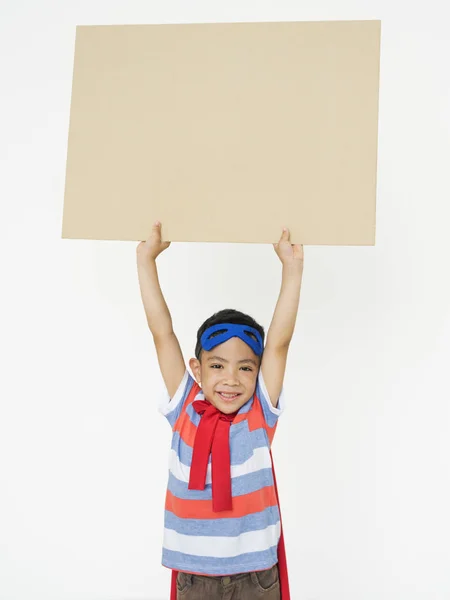 Мальчик-супергерой с картонкой в руках — стоковое фото