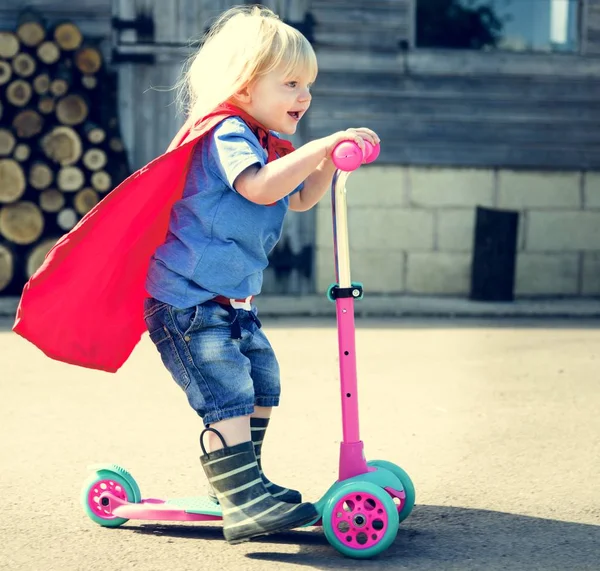 Superhero chłopiec jazdy skuterem — Zdjęcie stockowe