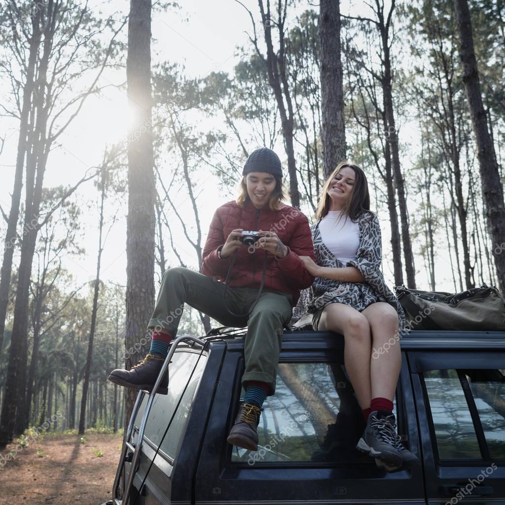 Couple of travelers sitting on car 