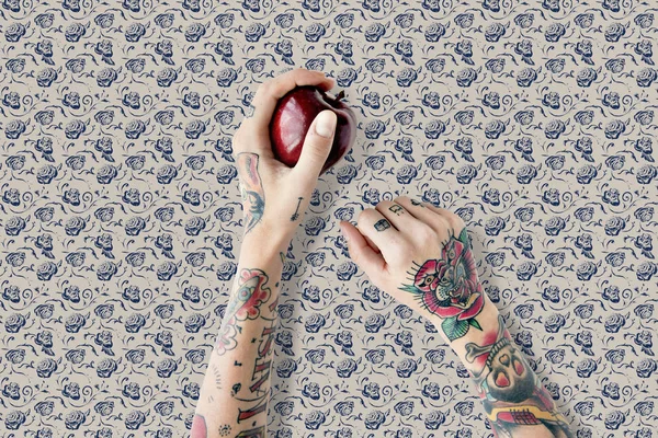 Mãos em tatuagens contém maçã — Fotografia de Stock