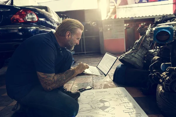 Автомеханик с ноутбуком в гараже — стоковое фото